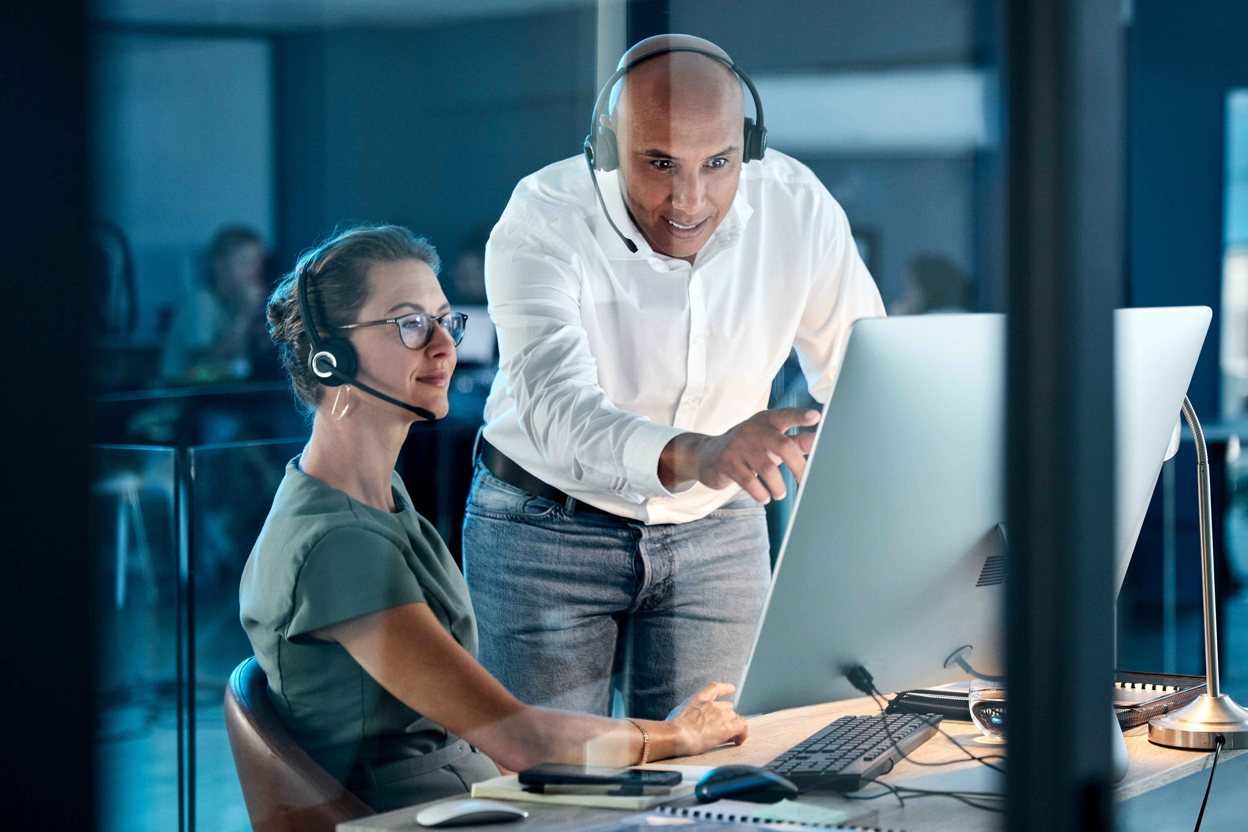 a woman and a man are working together at a computer station